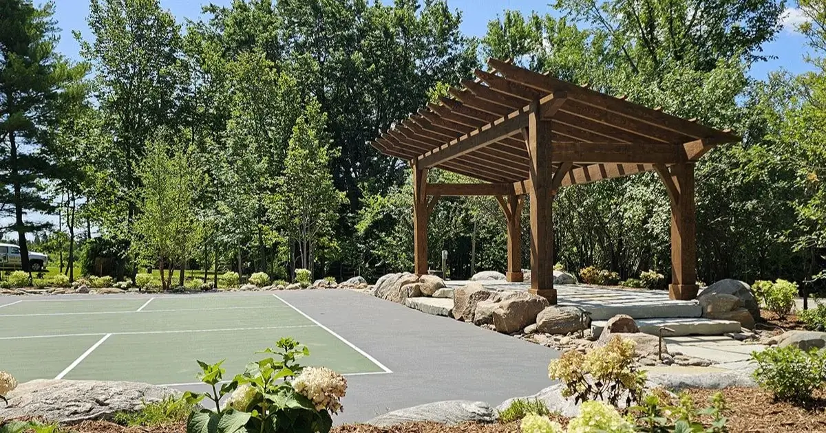 Custom timber pergola beside outdoor sport court with landscaped stone border