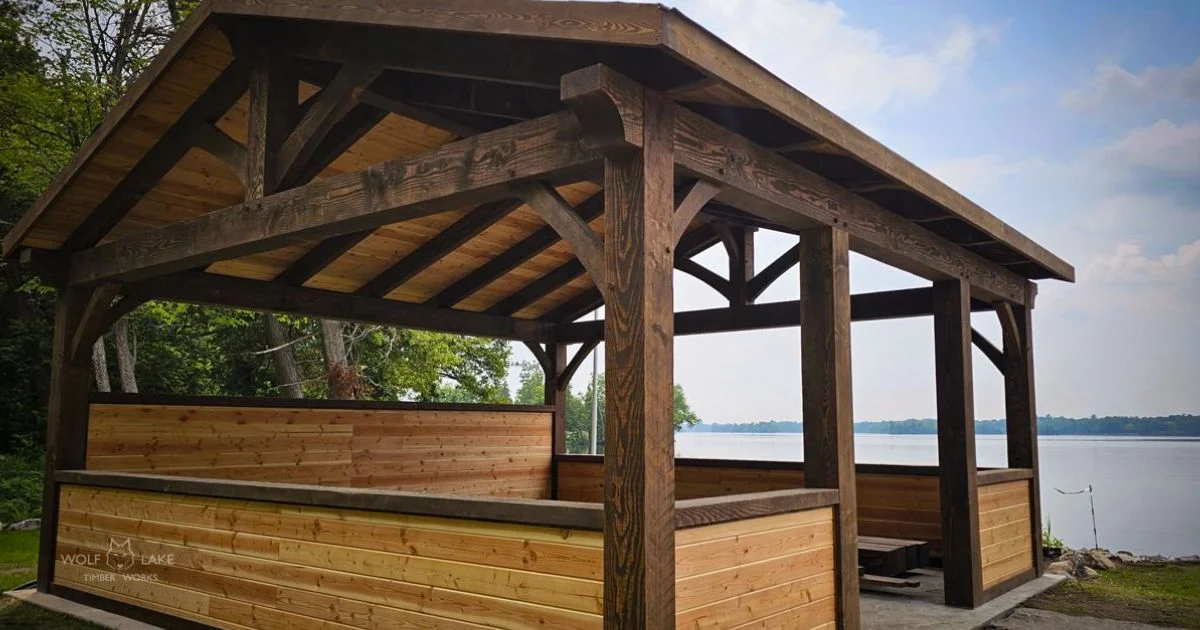 Lakefront timber frame pavilion with wood beams and bench seating